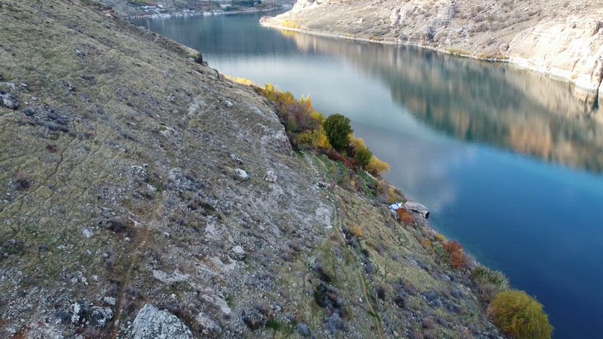 Eğil Barajı çevresindeki doğal güzellikleri gösteren profesyonel drone videosu. Durgun göl yüzeyi, kayalık arazi, kırsal peyzaj ve bölgenin özgün doğası görüntülenmektedir.