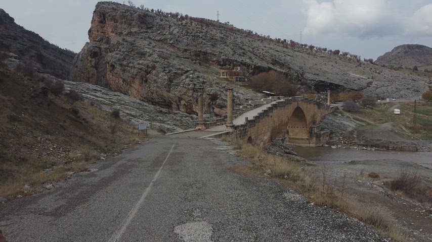 Adıyaman'da bulunan tarihi Cendere Köprüsü'nün drone ile çekilmiş görüntüsü. Roma döneminden kalan taş köprü, çevresindeki dağlık arazi ve yürüyen ziyaretçi ile birlikte tarihi ve kültürel mirası yansıtmaktadır.