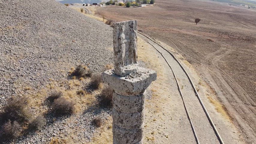 Adıyaman Arsemia Antik Kenti'nde bulunan Kommagene Krallığı dönemine ait tarihi kabartmalı taş sütunun drone ile çekilmiş yakın plan görüntüsü. Arkeoloji, tarih, kültürel miras ve turizm temaları için uygundur.