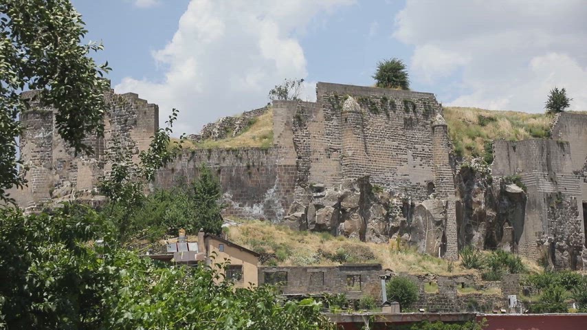 Bitlis Kalesi'nin tarihi taş duvarlarını ve çevresindeki şehir dokusunu gösteren yüksek kaliteli stok video.