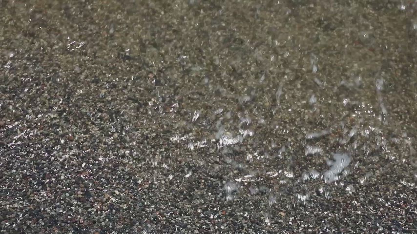 Van Gölü kıyısında kum ve çakıl taşlarına ulaşan hafif su dalgalarının doğal hareketini gösteren yüksek kaliteli stok video.