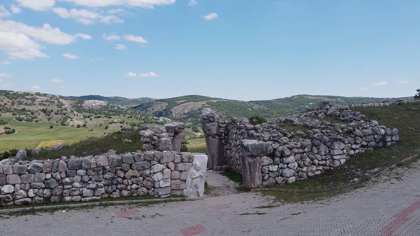 Hattuşa Antik Kenti'ndeki taş sur kapısını ve Hitit savunma yapılarının drone görüntüsünü gösteren tarihi stok video.