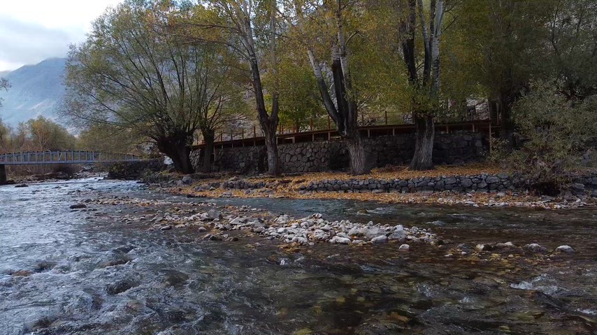 Dersim Munzur Çayı'nın taşlı kıyıları, sonbahar renkleri ve berrak akarsuyunu gösteren sinematik stok görüntü.