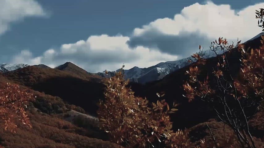 Dersim'in sonbahar vadileri ve karlı dağ zirvelerini bulutlu gökyüzü eşliğinde gösteren doğal manzara.