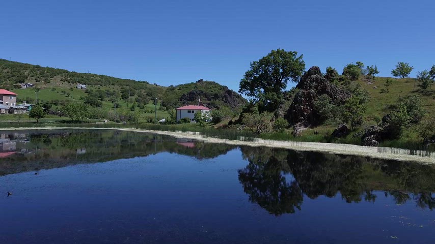 Dersim'deki Xızır Gölü kıyısında suya yansıyan ağaçlar ve doğal manzarayı gösteren sinematik doğa görüntüsü.