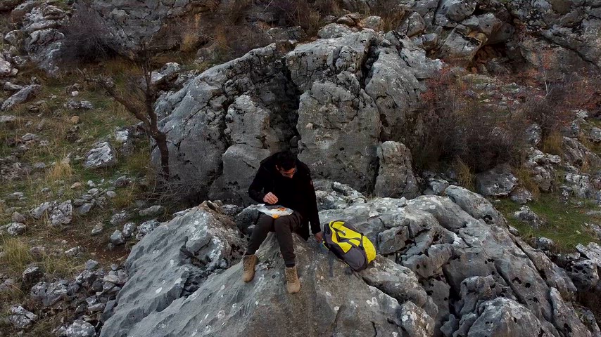 Çermik Sinek Çayı vadisinde kayalıklar üzerinde oturan kişinin drone görüntüsü.