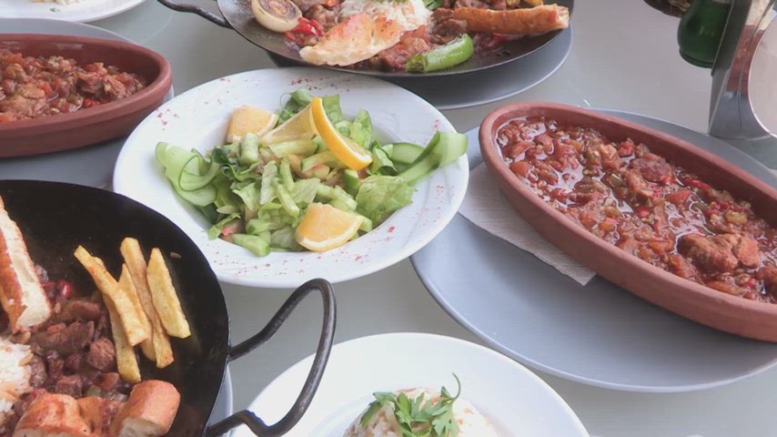 Çömlek güveç, et yemekleri, pilav ve salata çeşitlerini gösteren geleneksel sofra sunumu ve yemek videosu.
