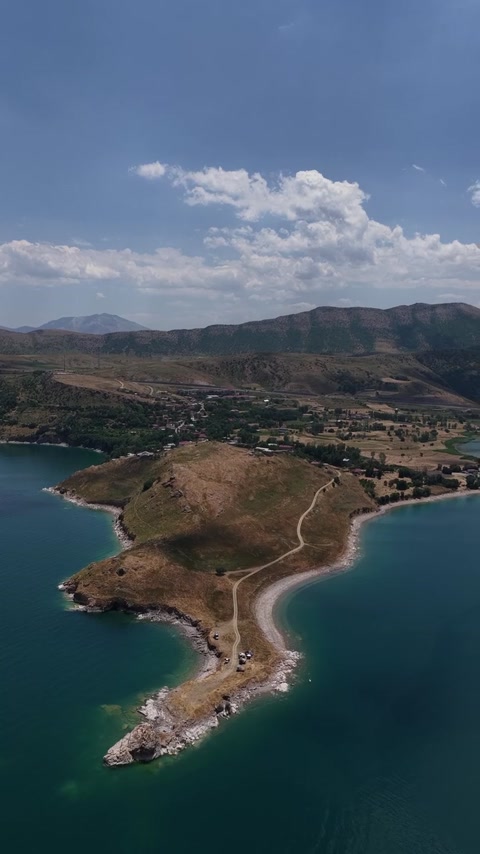 Van Gölü kıyısındaki doğal yarımada, turkuaz koylar ve dağ manzarasını havadan gösteren etkileyici doğa görüntüsü.